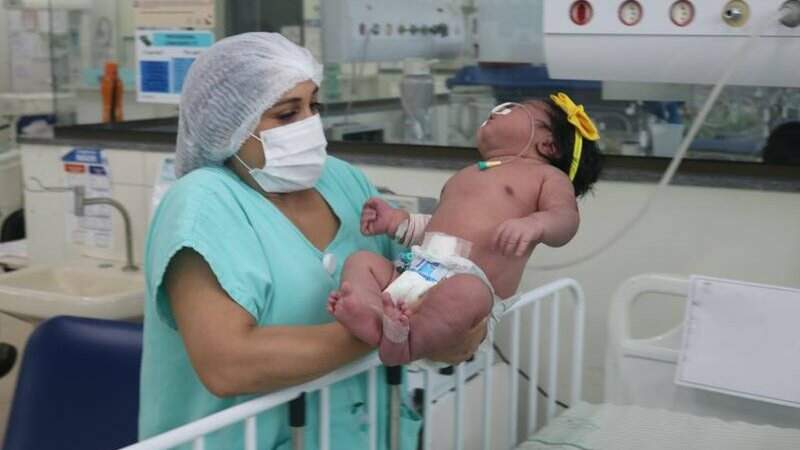 Na foto, a bebê está sendo colocada em um berço maior pois não coube na incubadora