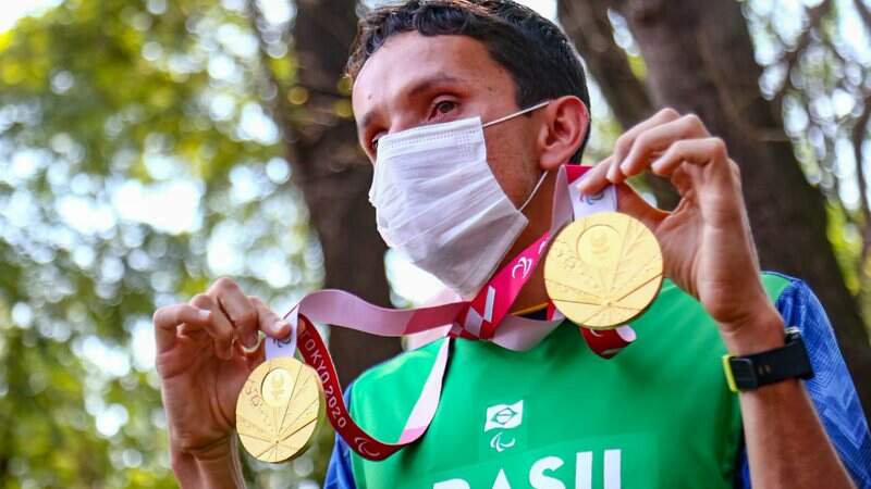 Campeão paralímpico exibindo as medalhas de Tóquio na concentração para carreata no Horto Florestal