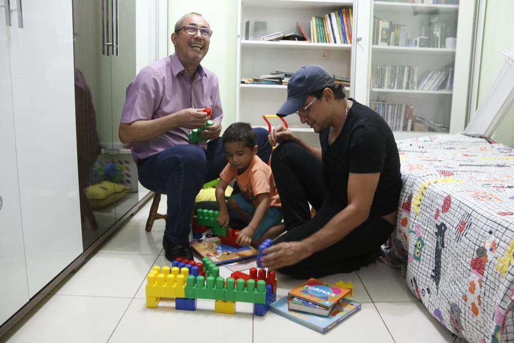 Os papais exercendo uma das funções de pai, brincar com o filho 