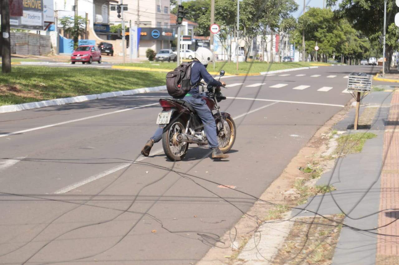 Motociclista se enrosca em fiação solta na rua.