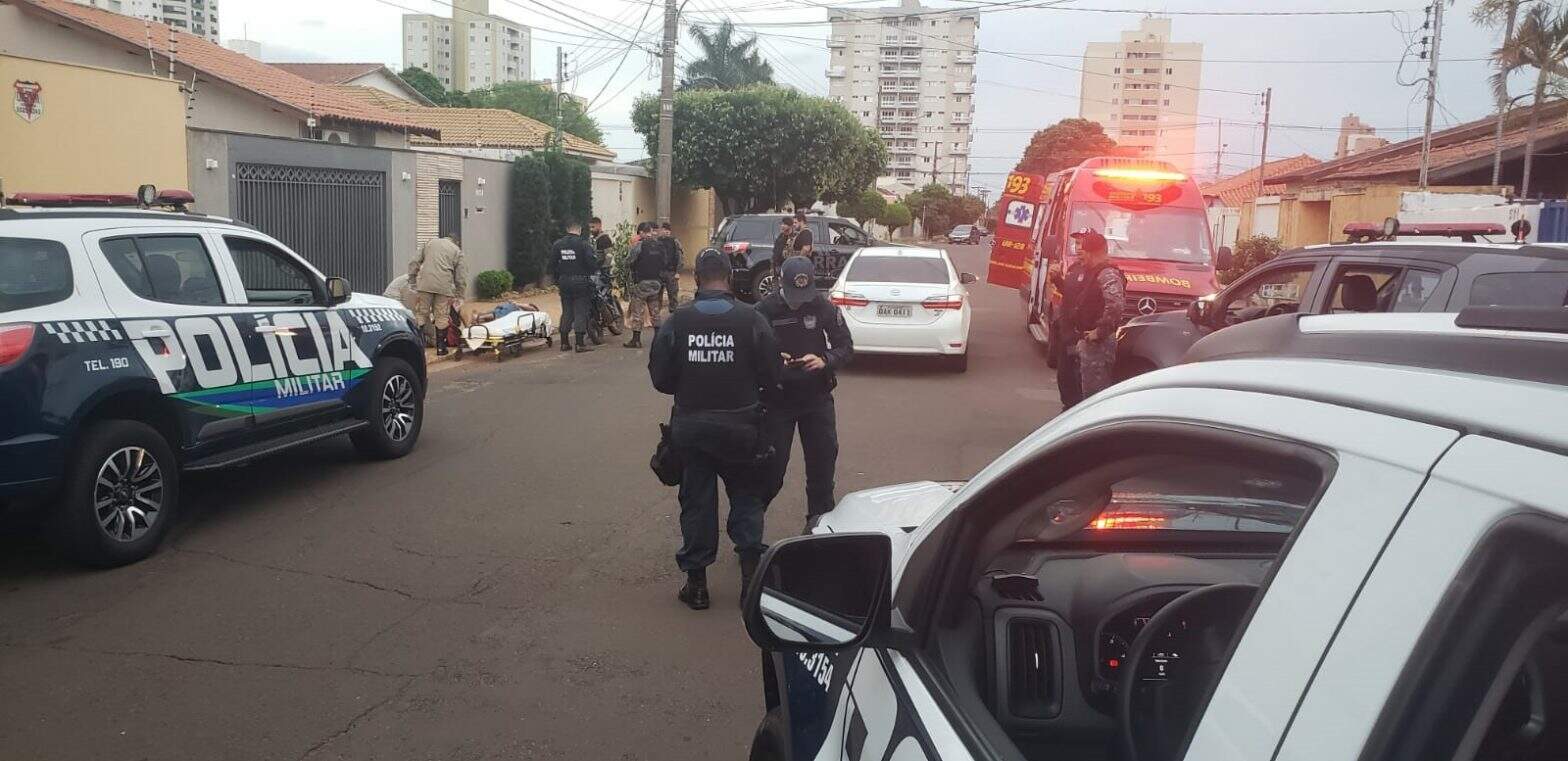 Homem sendo socorrido enquanto policiais isolam o local