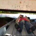 VÍDEO: rio sobe 5 metros e pescadores deitam em barco para passar por ponte