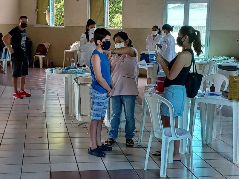 Criança acompanhada da mãe recebendo primeira dose da vacina contra a Covid-19