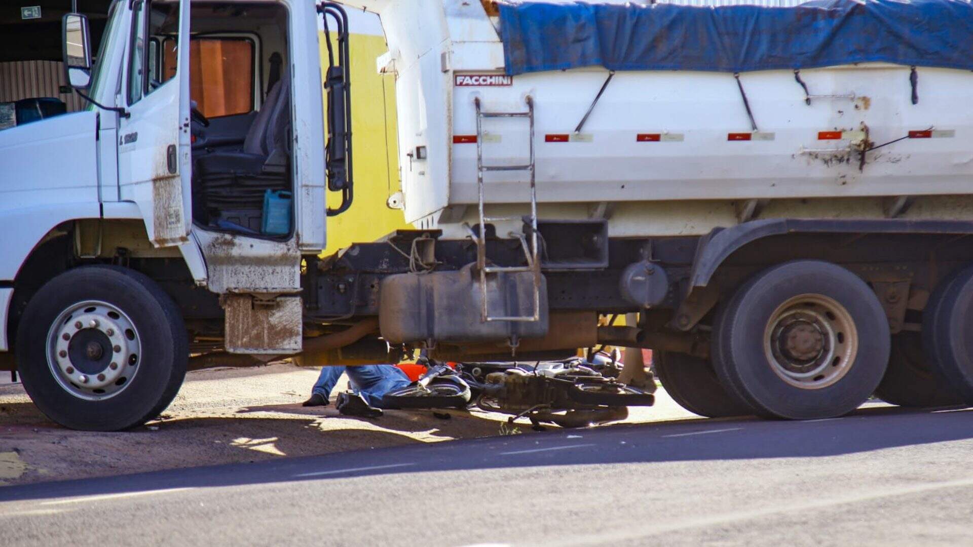 Motociclista é socorrido após colidir em caminhão caçamba carregado de areia